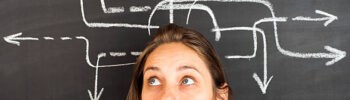 choix_istock_marrio31_613543010 Arrow sketch on blackboard and pretty young woman smiling to camera. Concept of decision making